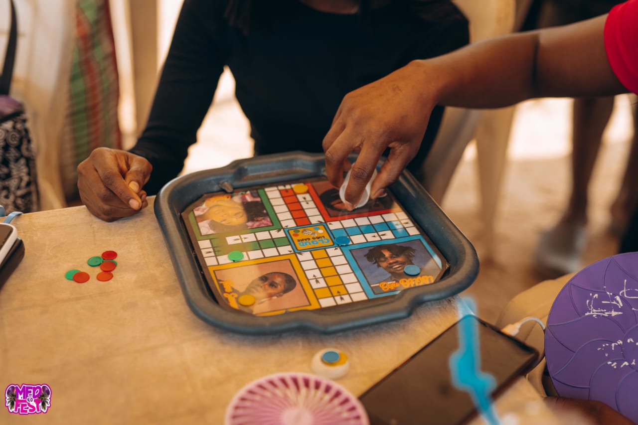A hand playing a Ludo board game